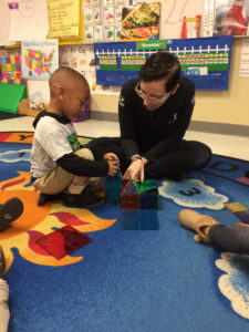 Pre-K tutor working with students at center time